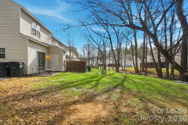 a backyard of a house with plants and large tree