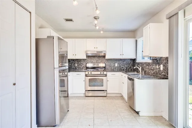 a kitchen with a refrigerator and white cabinets
