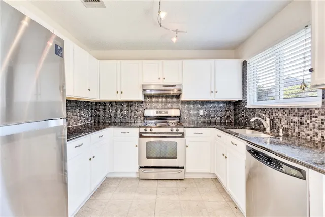 a kitchen with granite countertop white cabinets and white appliances