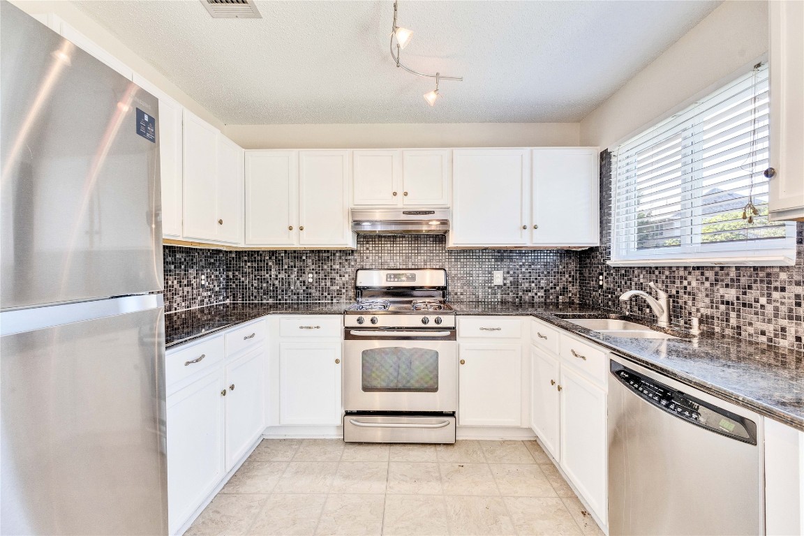 3600 Cheyenne Street Round Rock, TX 78665 - Photo 10 of 36 a kitchen with granite countertop white cabinets and white appliances