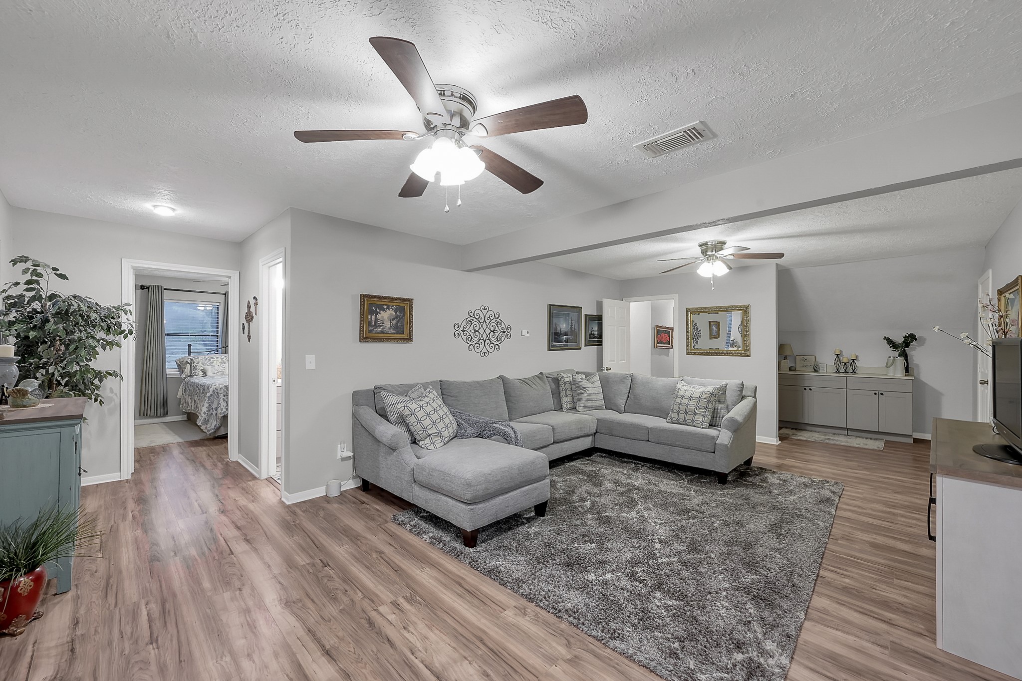 80 Nettie Phillips Road Coldspring, TX 77331 - Photo 20 of 49 Upstairs Living Area with views of a guest bedroom on the left, additional storage/dry bar on the right and primary hallway on the center. Notice the beautiful flooring and ceiling fans.
