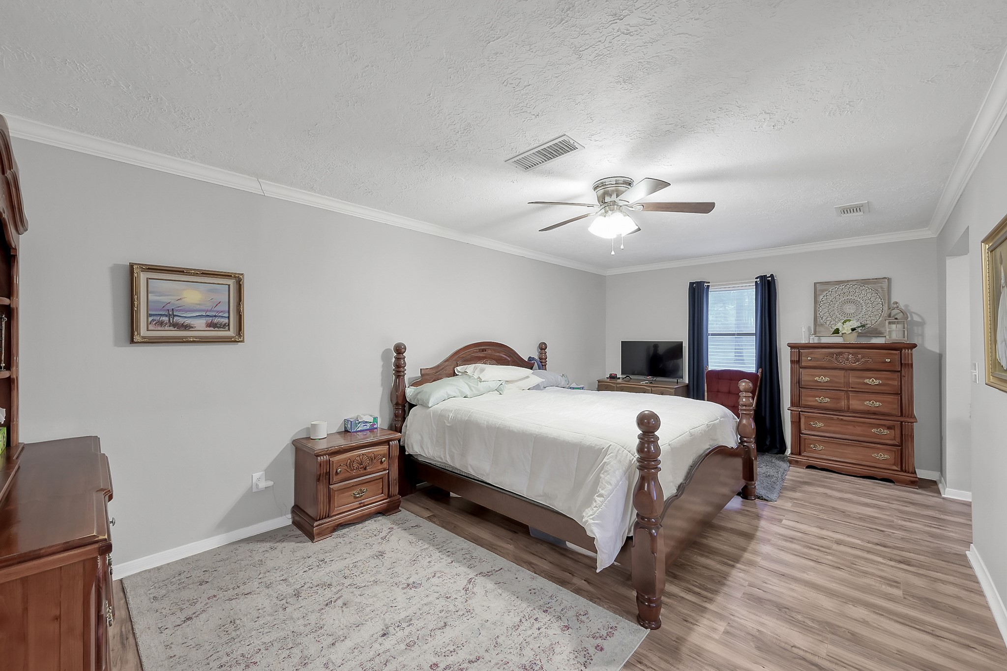 80 Nettie Phillips Road Coldspring, TX 77331 - Photo 24 of 49 Upstairs Primary Suite with crown molding and ceiling fan, with hard flooring.