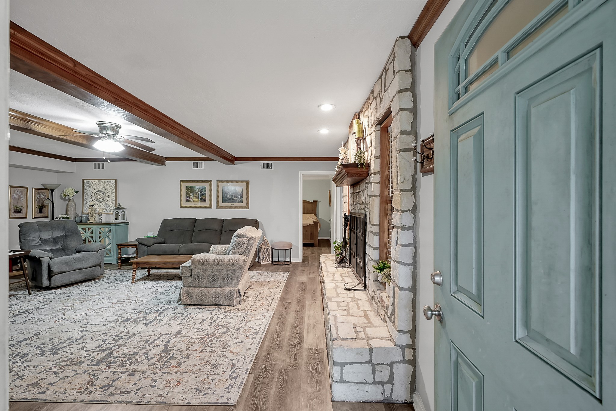 80 Nettie Phillips Road Coldspring, TX 77331 - Photo 6 of 49 Enter through the front door into the welcoming Living Area with focal point stone fireplace. Wood beams overhead and engineered wood at your feet invites you into the home.