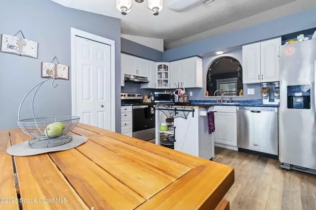 a kitchen with stainless steel appliances kitchen island granite countertop a sink dishwasher and cabinets with wooden floor