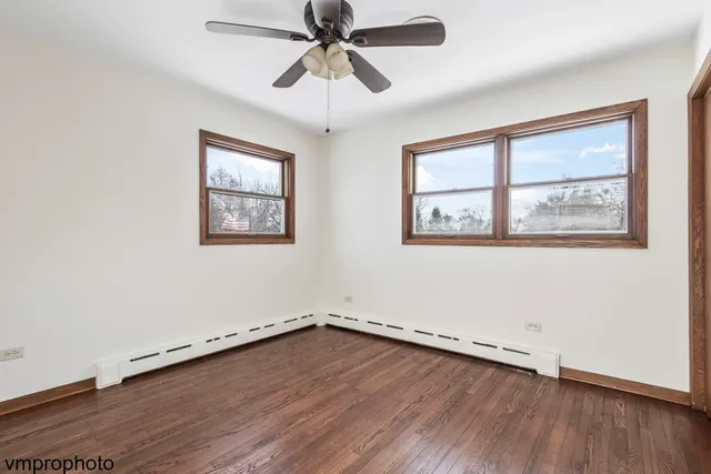 an empty room with wooden floor ceiling fan and windows
