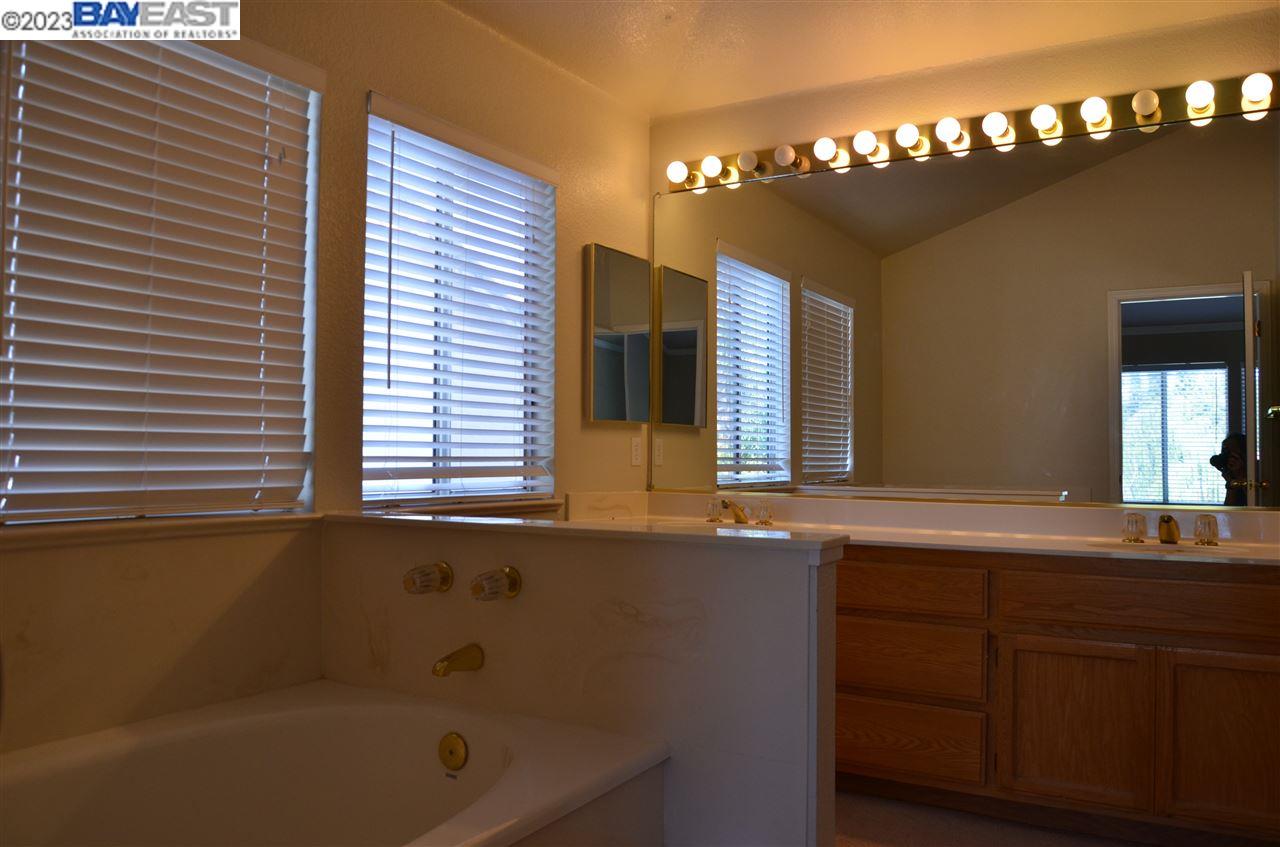 1463 Egret Drive Tracy, CA 95376 - Photo 19 of 19 a bathroom with a tub a sink and a large mirror