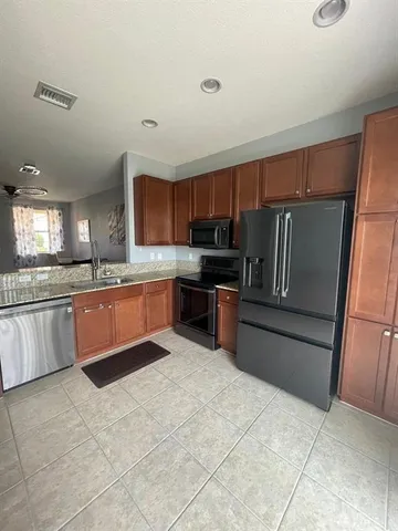 a large kitchen with granite countertop a refrigerator and a stove top oven