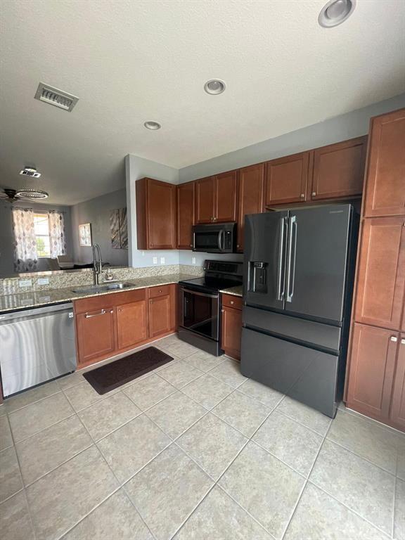 7445 Sarentino Lane, Unit 219 Boynton Beach, FL 33437 - Photo 3 of 12 a large kitchen with granite countertop a refrigerator and a stove top oven