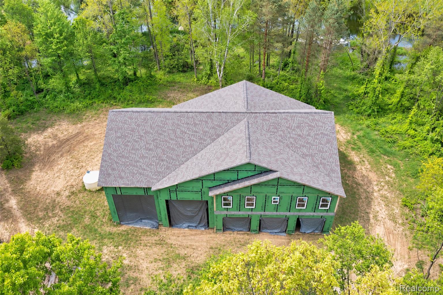 1601 West Rose Center Road Holly, MI 48442 - Photo 1 of 14 New construction with partial siding, multiple garage door openings, and a grey shingle roof