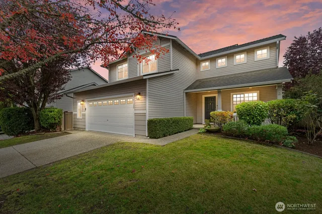 a view of a house with a yard and large tree