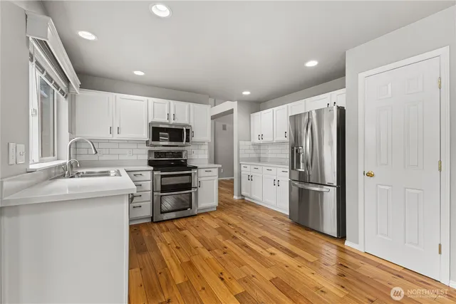 a kitchen with white cabinets and appliances