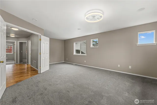 an empty room with chandelier fan and windows