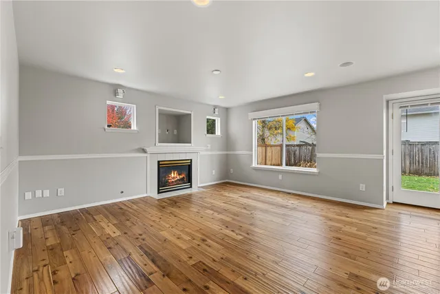 an empty room with windows fireplace and wooden floor