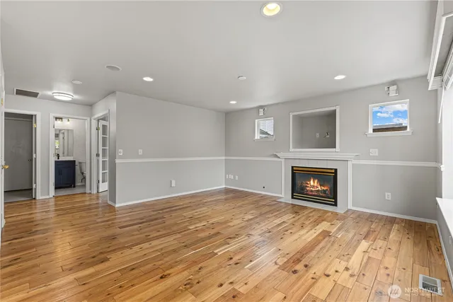 a view of an empty room with wooden floor and a fireplace