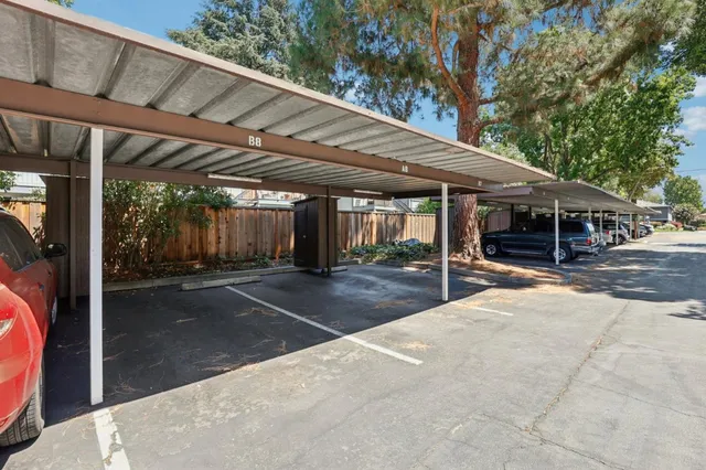 a view of a patio with table and chairs under an umbrella with a barbeque