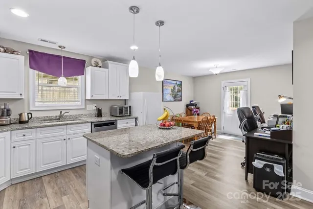 a kitchen with a stove a sink dishwasher a dining table and chairs with wooden floor