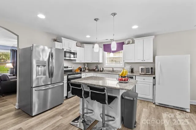 a kitchen with stainless steel appliances a refrigerator a stove a sink dishwasher a oven with white cabinets and wooden floor