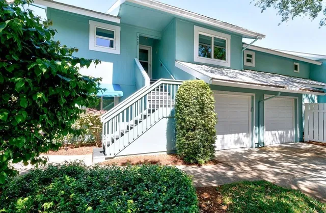 a view of a house with a small yard plants and large tree