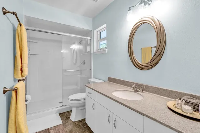a bathroom with a granite countertop toilet a sink and a mirror