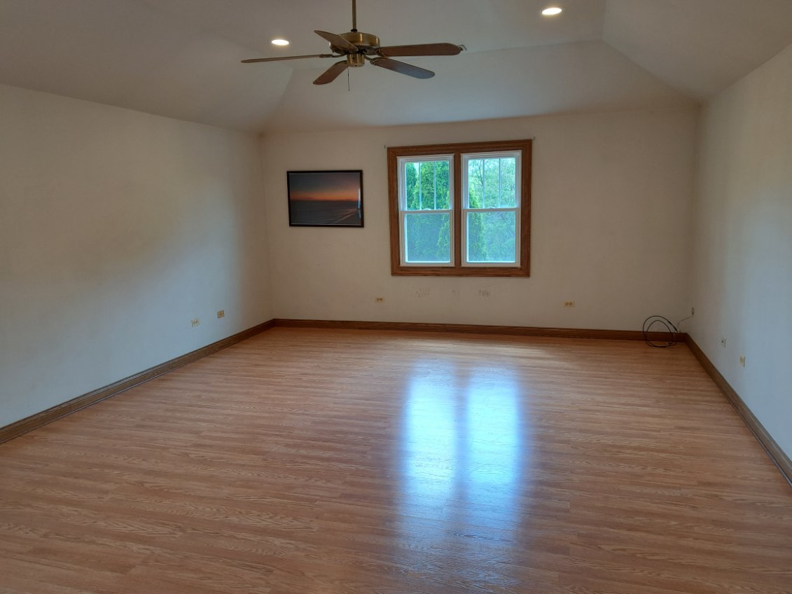 Undisclosed Address Park Ridge, IL 60068 - Photo 13 of 25 an empty room with wooden floor chandelier fan and windows