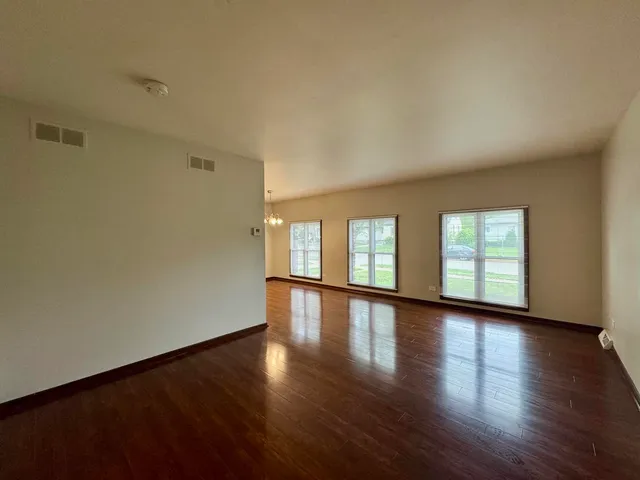 a view of an empty room with wooden floor and window