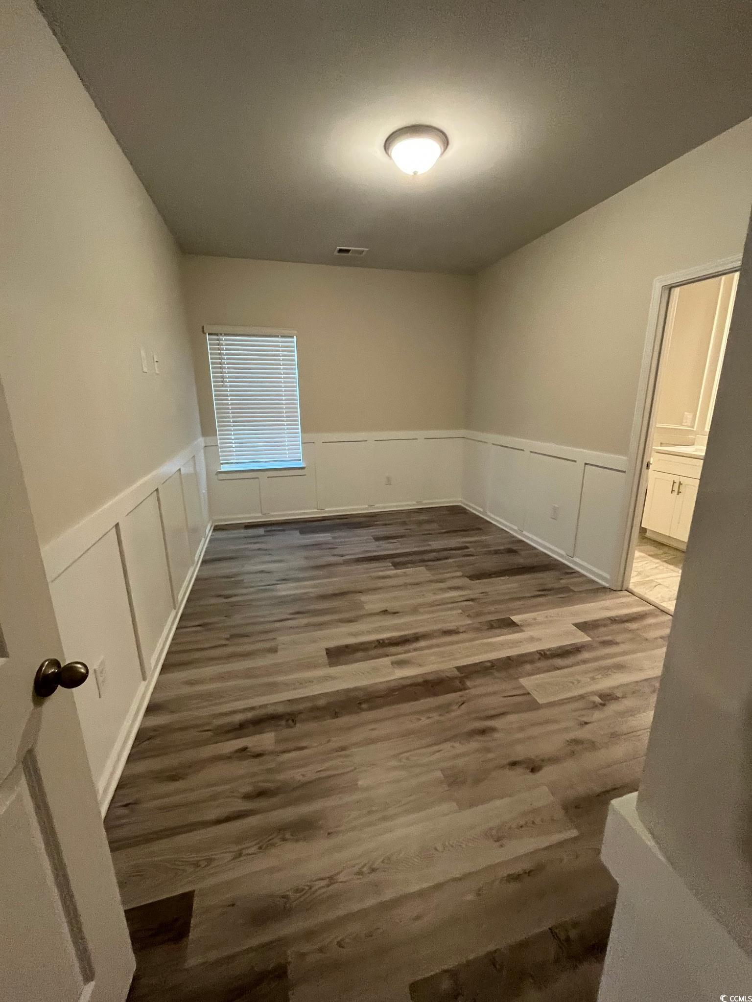 1505 1st Avenue Conway, SC 29526 - Photo 3 of 9 Empty room featuring wainscoting, dark wood-type flooring, and a decorative wall