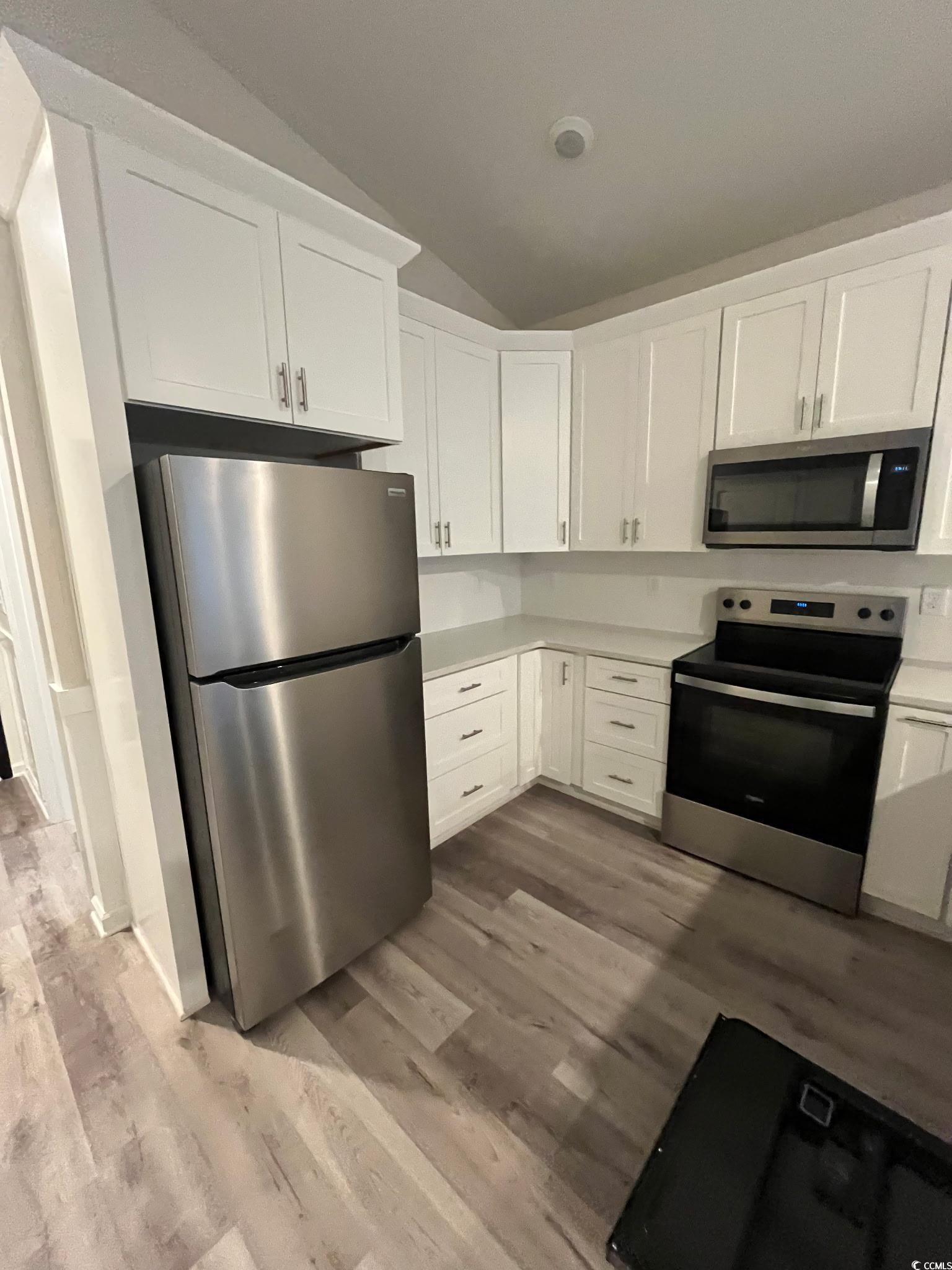 1505 1st Avenue Conway, SC 29526 - Photo 4 of 9 Kitchen featuring stainless steel appliances, vaulted ceiling, white cabinets, light countertops, and dark wood-style flooring