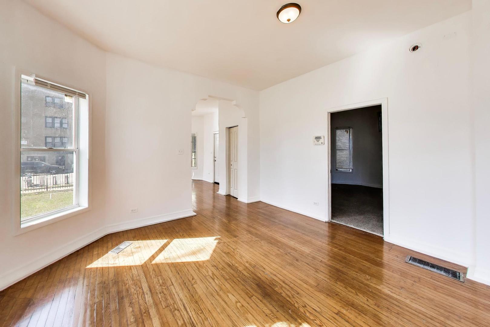 6853 South Perry Avenue Chicago, IL 60621 - Photo 7 of 28 a view of an empty room with wooden floor and a window
