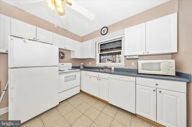 a kitchen with granite countertop white cabinets white appliances and a sink
