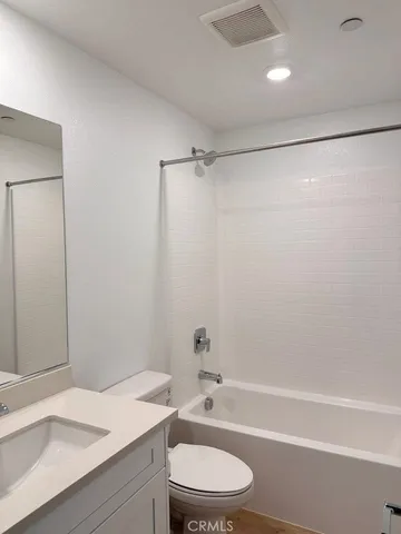 a bathroom with a granite countertop bathtub shower sink vanity and toilet