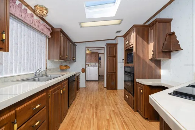 a kitchen with stainless steel appliances a sink dishwasher stove refrigerator and wooden cabinets