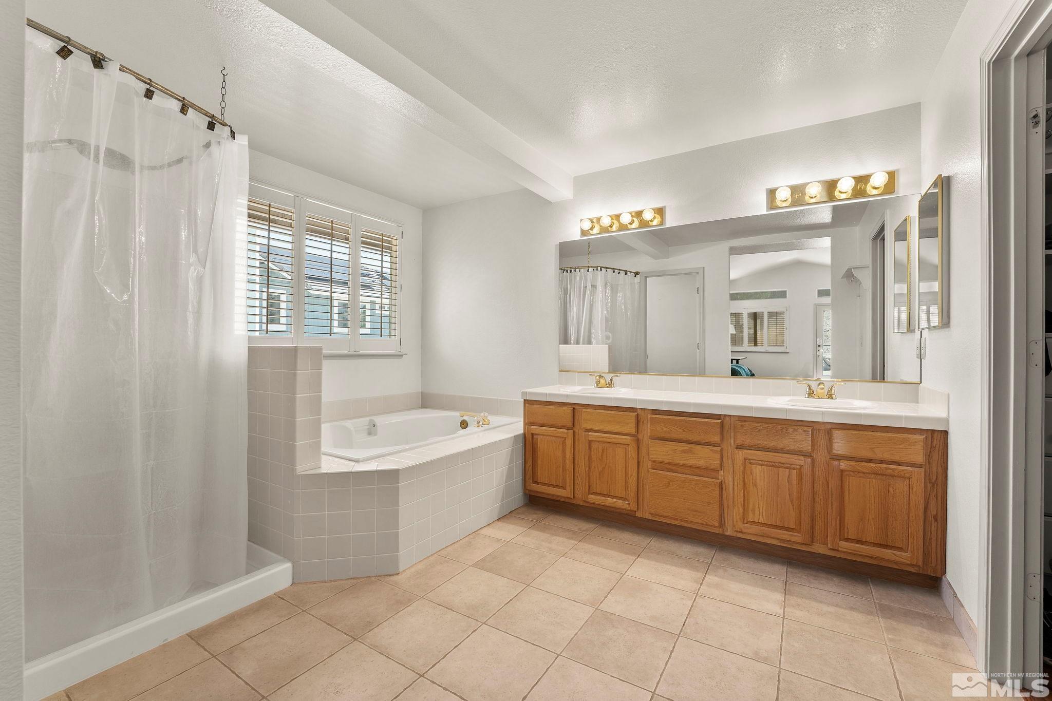 50 Deer Valley Court Reno, NV 89511 - Photo 20 of 39 a spacious bathroom with a double vanity sink a mirror a bathtub and next to a window