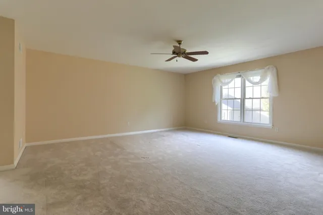 an empty room with windows and ceiling fan view