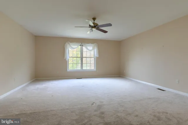 an empty room with windows and ceiling fan