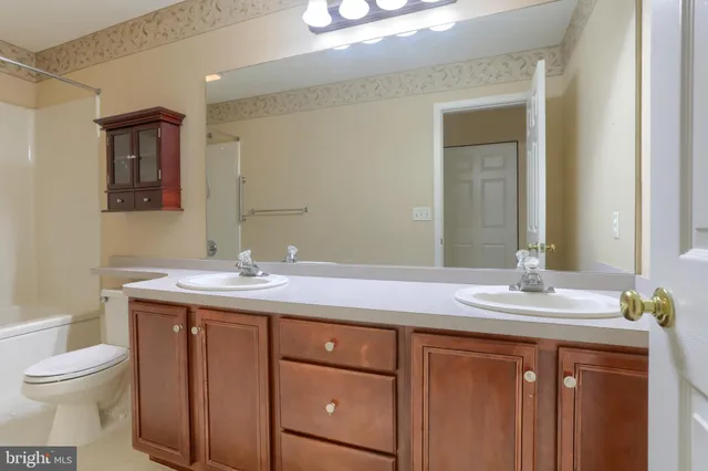 a bathroom with a granite countertop sink a toilet and a mirror