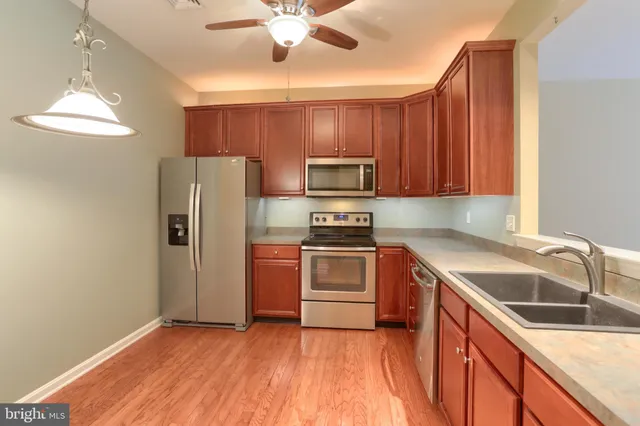 a kitchen with stainless steel appliances granite countertop a refrigerator a sink dishwasher and a stove with wooden floor