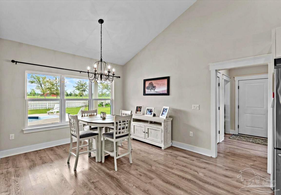 7400 Tidwell Road Pace, FL 32571 - Photo 22 of 36 a dining room with wooden floor a chandelier a wooden table and chairs