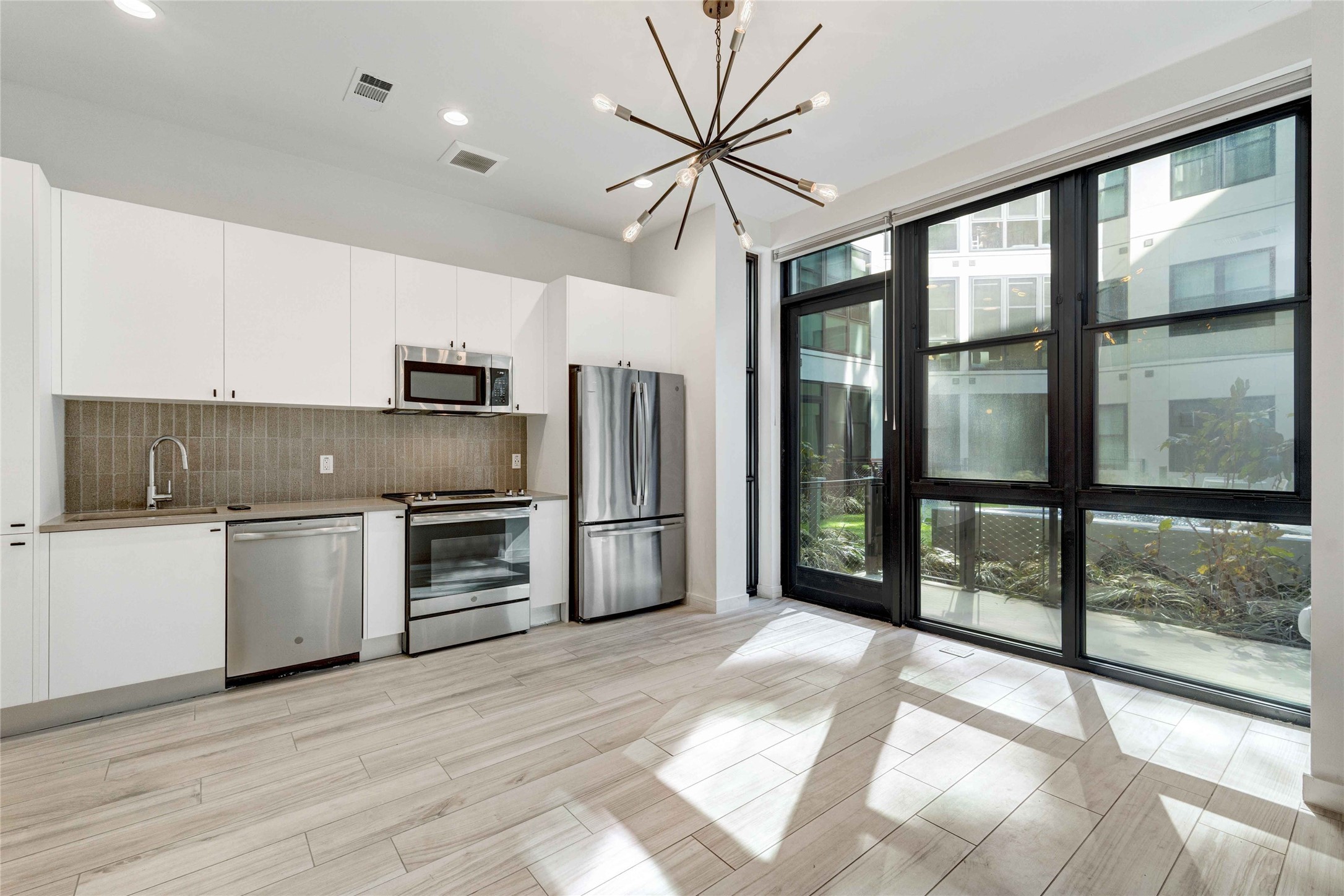 800 Embassy Drive, Unit 123 Austin, TX 78702 - Photo 2 of 39 a kitchen with a refrigerator a stove top oven and a large window with wooden floor