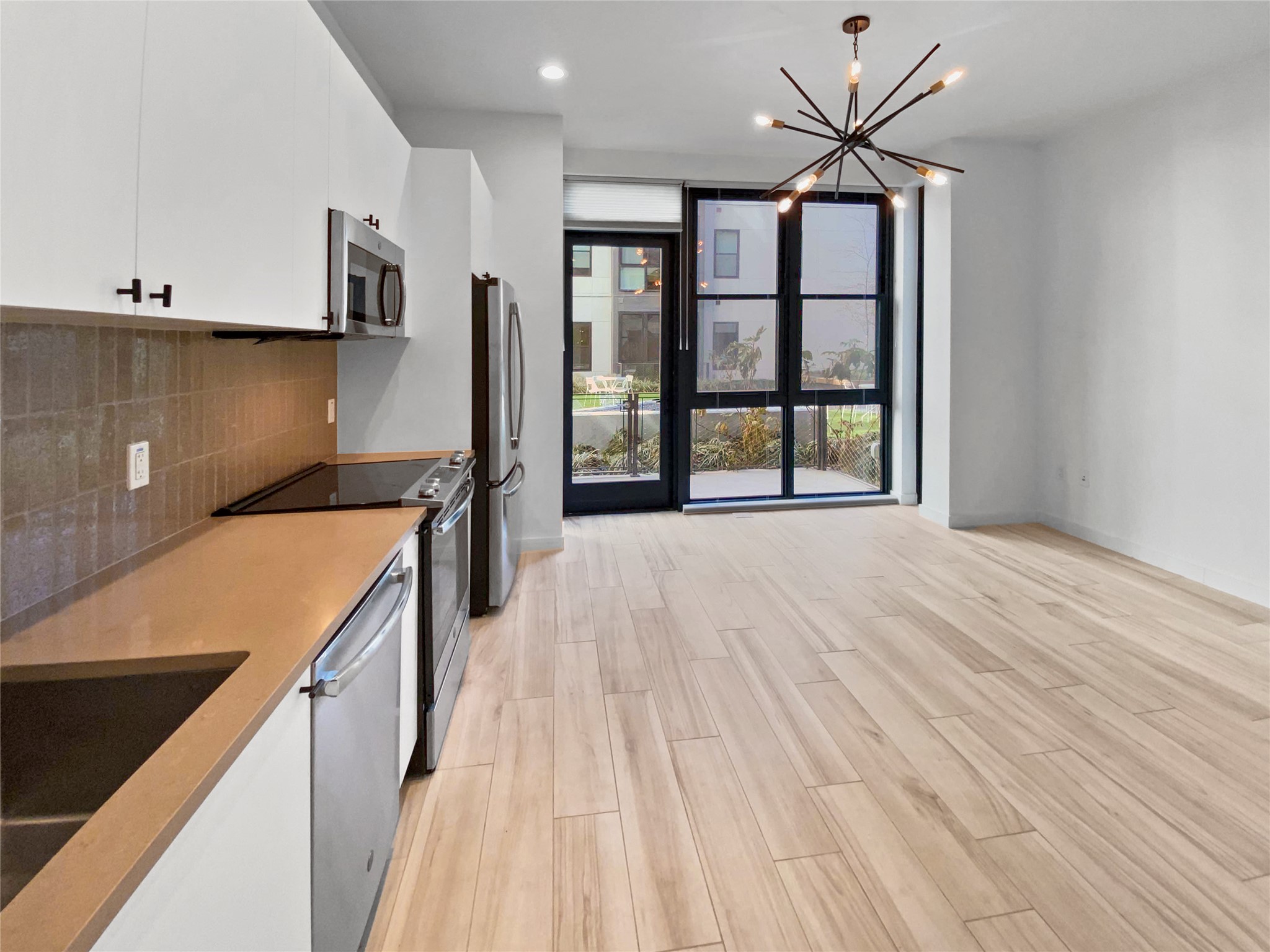 800 Embassy Drive, Unit 123 Austin, TX 78702 - Photo 4 of 39 a view of a kitchen with kitchen island a sink wooden floor and a large window
