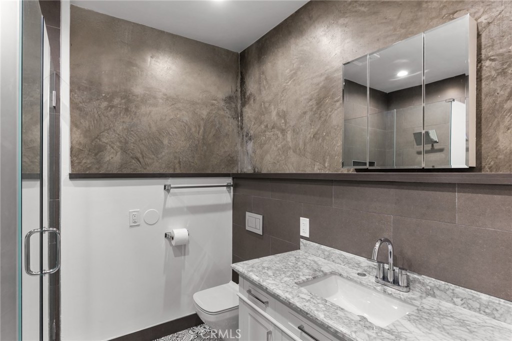 2211-1.2 Hyperion Avenue, Unit 1/2 Los Angeles, CA 90027 - Photo 15 of 15 a bathroom with a granite countertop sink a toilet and a mirror