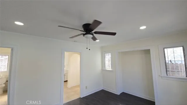 a view of empty room with wooden floor and ceiling fan