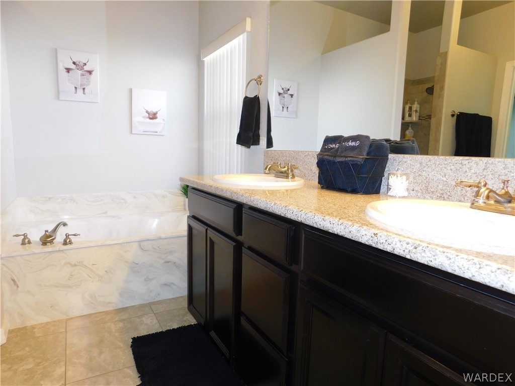 3370 South Ridge Avenue Bullhead City, AZ 86429 - Photo 37 of 56 a bathroom with a granite countertop sink a large mirror and a bathtub
