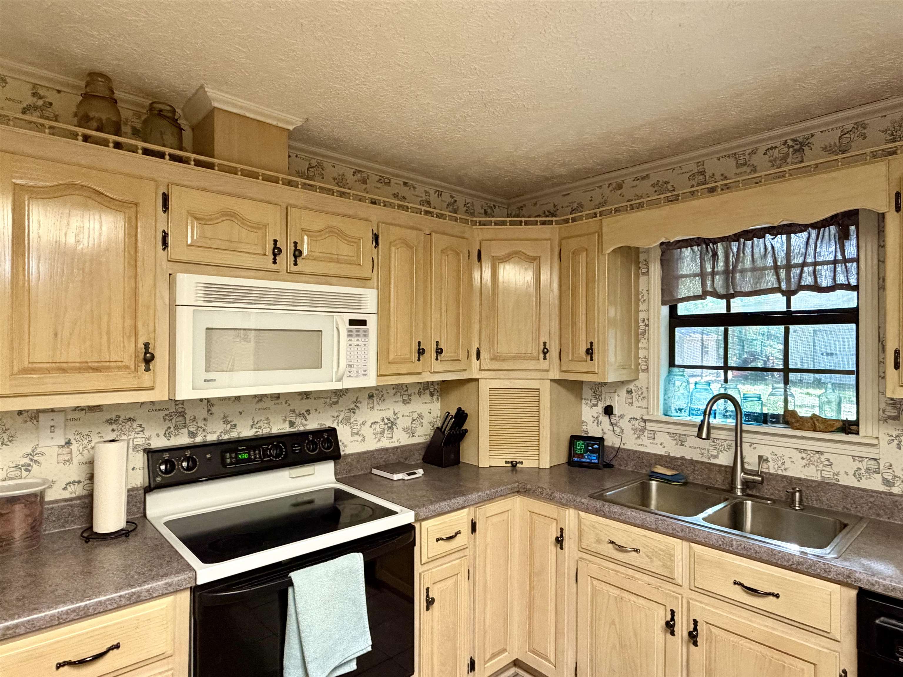 373 Clarence Barham Road Bethel Springs, TN 38315 - Photo 10 of 28 Kitchen featuring wood-finish cabinetry, built-in microwave, stainless steel double basin sink, black electric range, and light-toned countertops