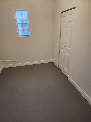 an empty room with a ceiling fan and window