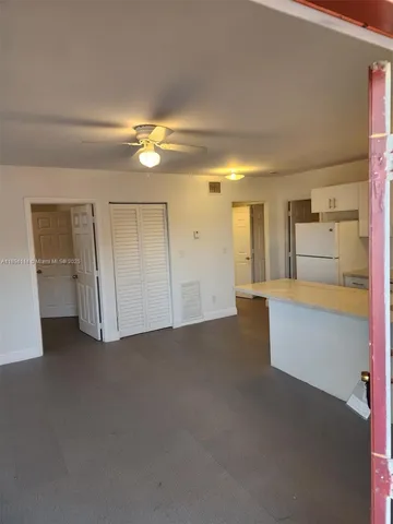 a view of an empty room with window and a kitchen