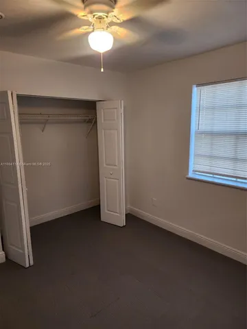 an empty room with a ceiling fan and a window