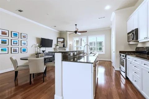 a kitchen with stainless steel appliances granite countertop a stove top oven a sink dishwasher a dining table and chairs with wooden floor