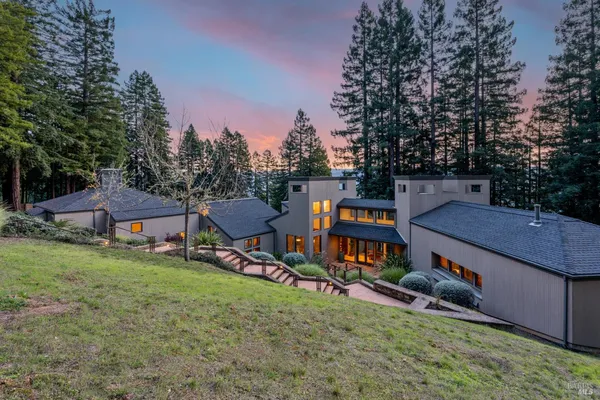 aerial view of a house with a yard balcony and trees