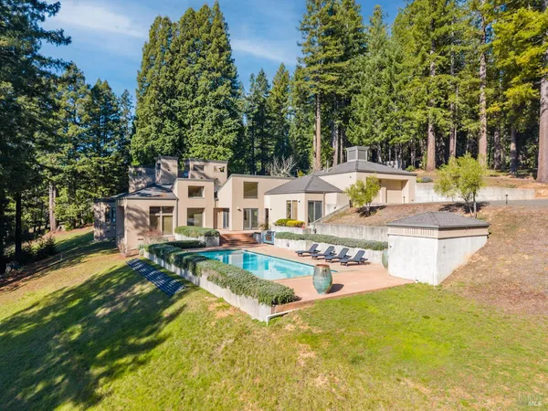 a view of a house with pool lawn chairs and a barbeque