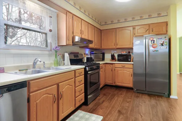 a kitchen with stainless steel appliances a sink cabinets and a window
